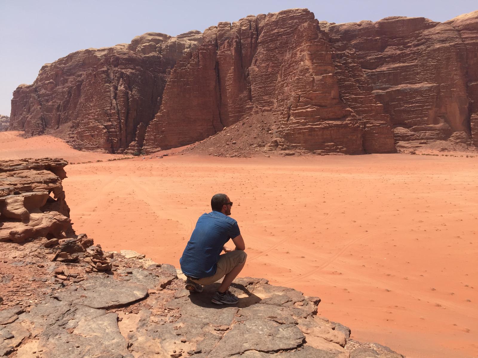 L’artiste assis face au désert du Wadi Rum, célèbre pour ses falaises rocheuses et son sable rouge.