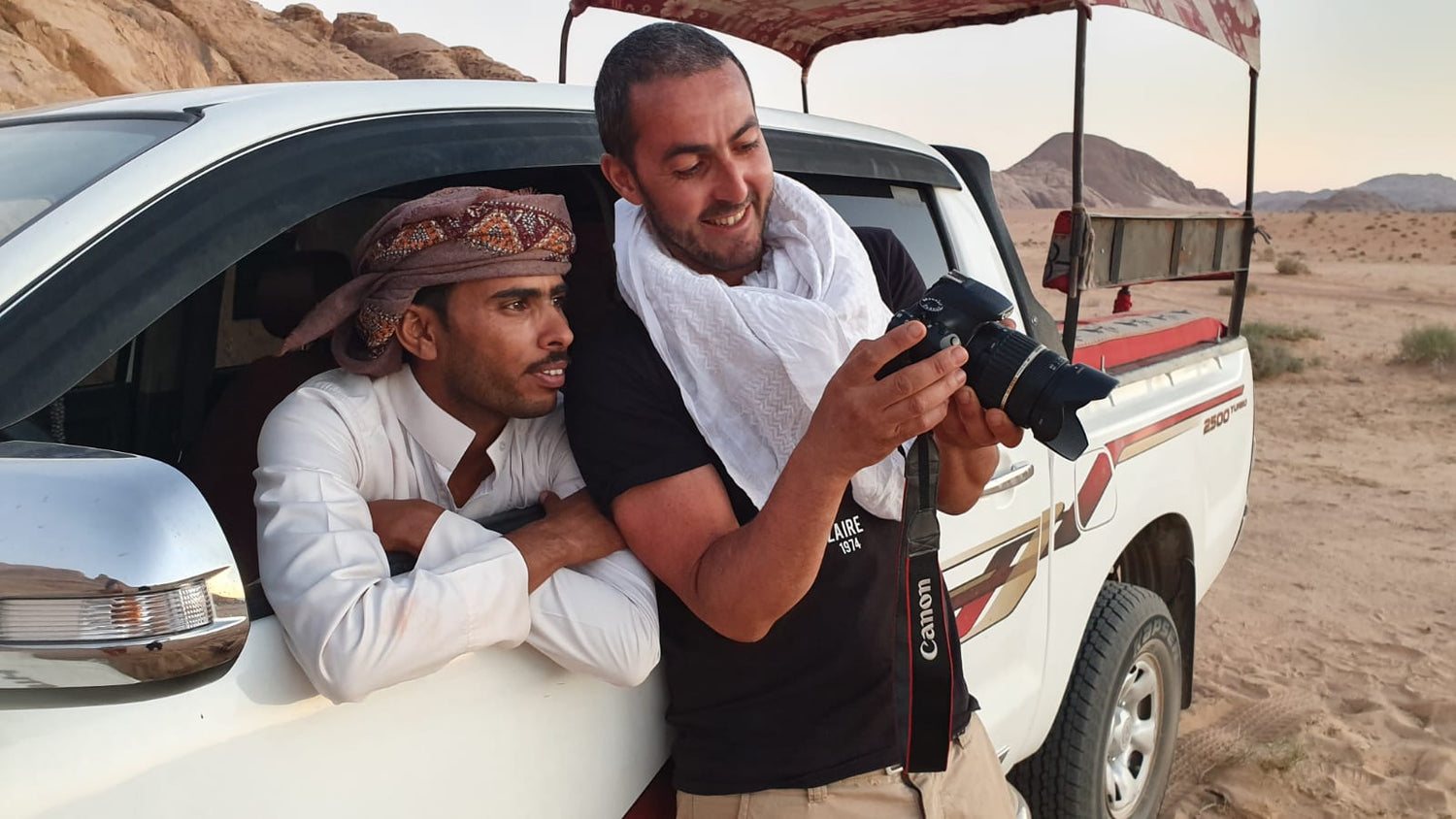 L’artiste échange avec son guide bédouin Salem dans le désert du Wadi Rum, en observant des photographies sur un appareil photo.