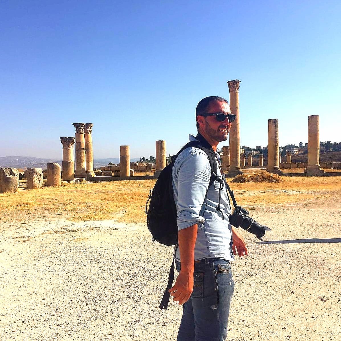 Artiste marchant sur le site romain de Jerash, entouré de colonnes antiques en Jordanie.