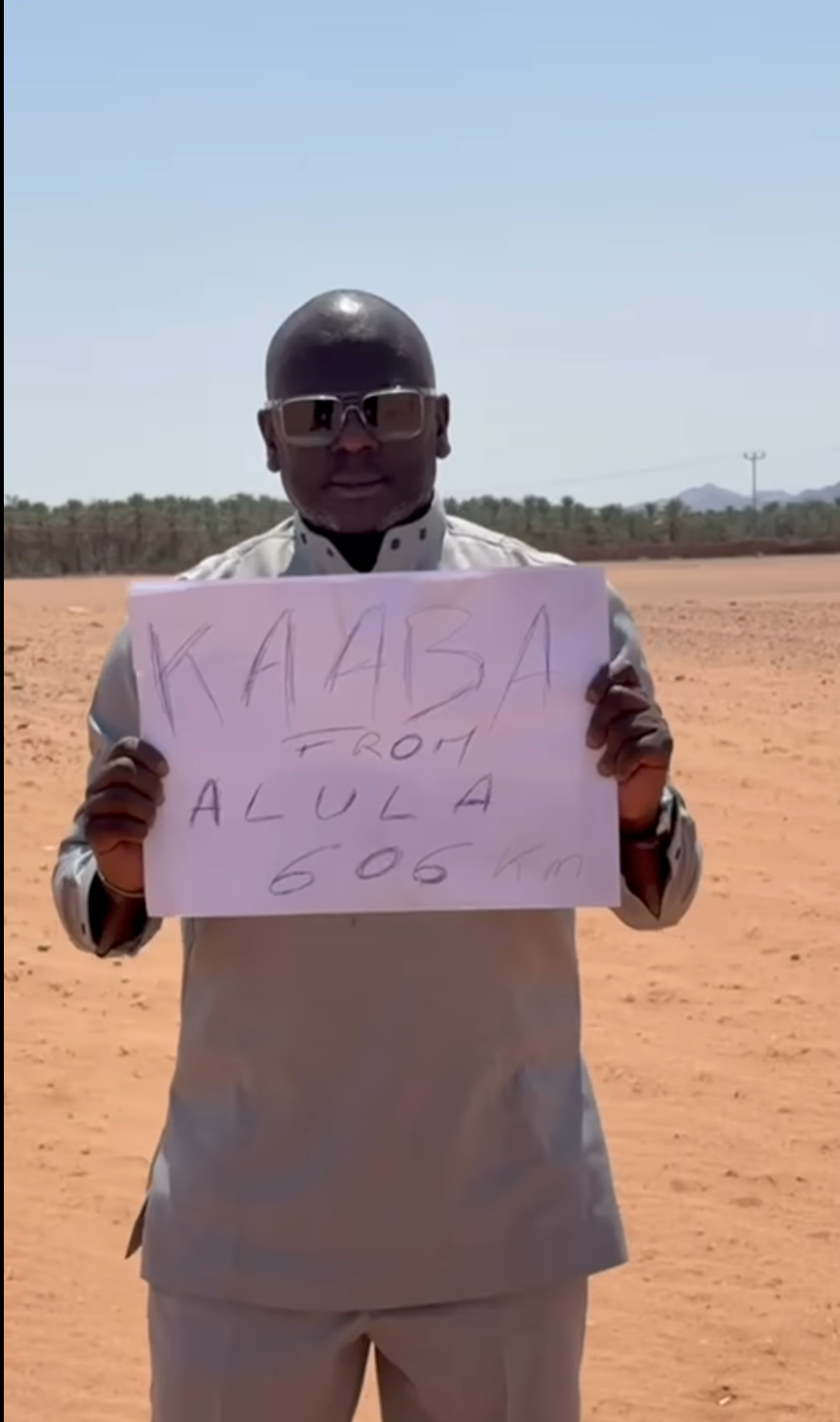 Personne tenant un message symbolique reliant un lieu du désert à la Kaaba
