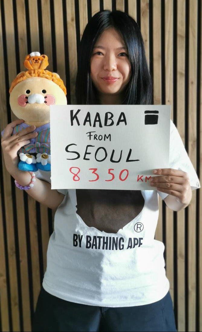 Personne tenant un message symbolique reliant un lieu du monde à la Kaaba
